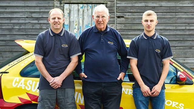 3 family members of Boundless standing in front of a yellow car
